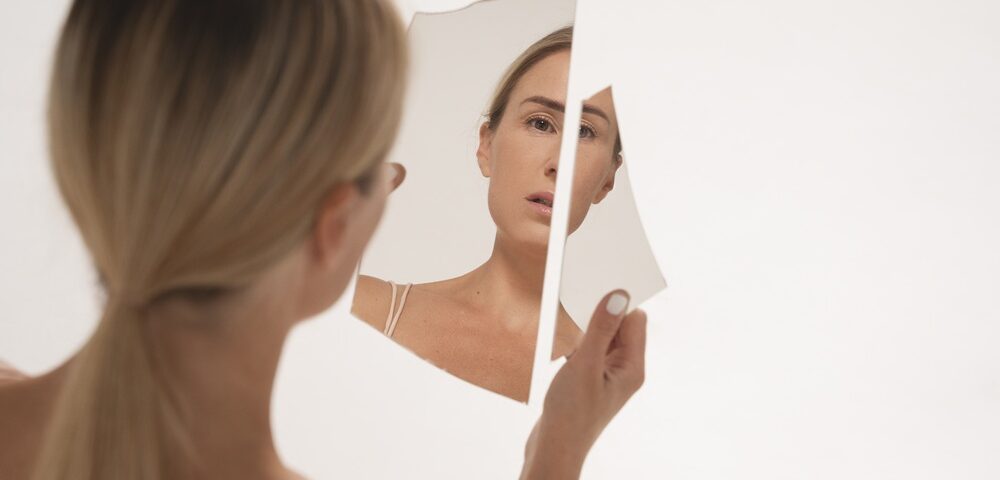 женщина держит разбитое зеркало