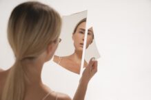 женщина держит разбитое зеркало